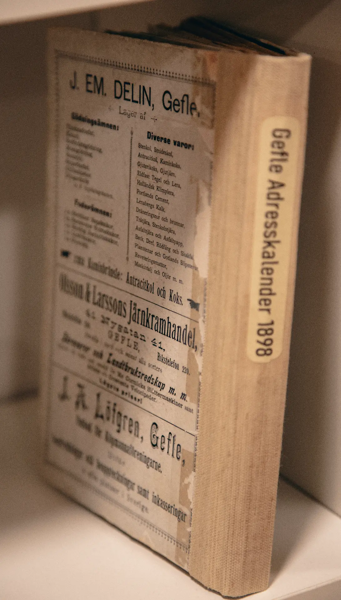Gammal bok i hylla med etiketten Gefle Adresskalender 1898